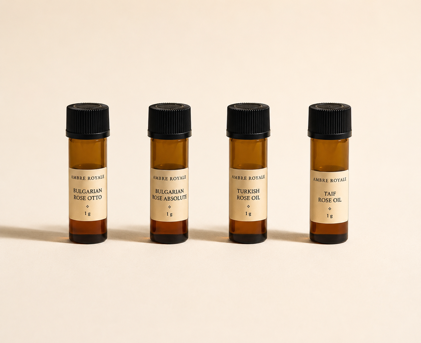 Four amber 1 g vials with black ribbed caps and Ambre Royale labels: Bulgarian Rose Otto, Bulgarian Rose Absolute, Turkish Rose Oil, Taif Rose Oil, on a warm cream background